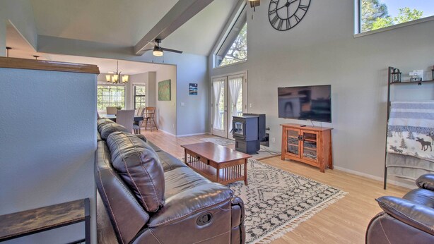 A spacious living room with a leather sofa, a wooden coffee table, and a TV. - Modern Show Low Retreat w/ Deck & Mtn Views! (Show Low)
