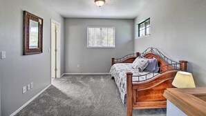 A bedroom with a wooden bed, a window with blinds, a ceiling light, and a door. - Modern Show Low Retreat w/ Deck & Mtn Views! (Show Low)