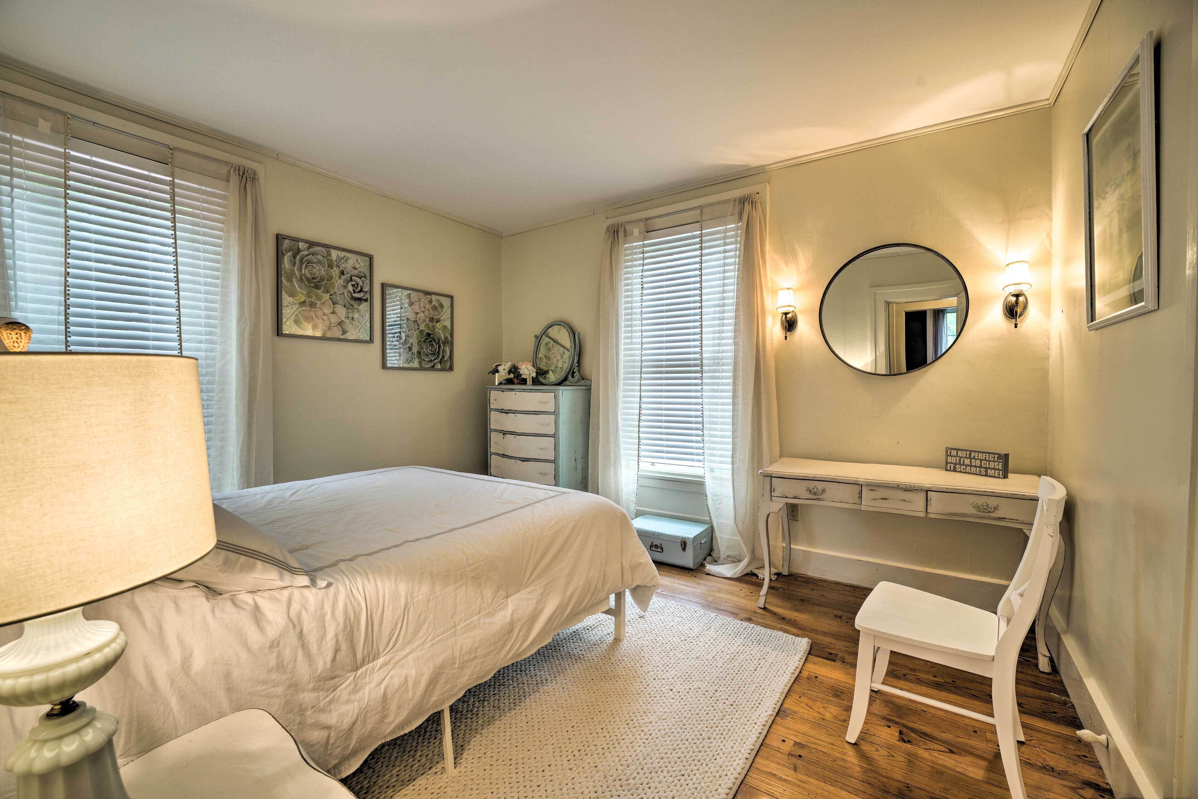 Un dormitorio con cama, escritorio, silla, lámpara y espejo.