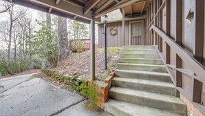 A staircase leading to a wooden door, surrounded by a brick wall and a wooden porch. - Breathtaking Brevard Home w/ Screened Porch! (Brevard)