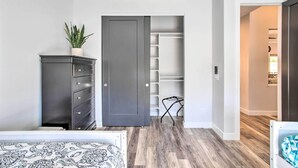 Un dormitorio con cama, cómoda, armario y planta en maceta.