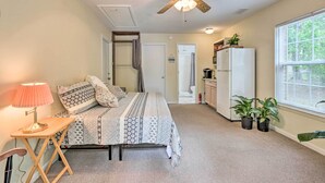 A bedroom with a bed, bedside table, lamp, ceiling fan, and potted plants. - Cozy Studio With Yard, 6 Miles to Dwtn Beaufort! (Beaufort)