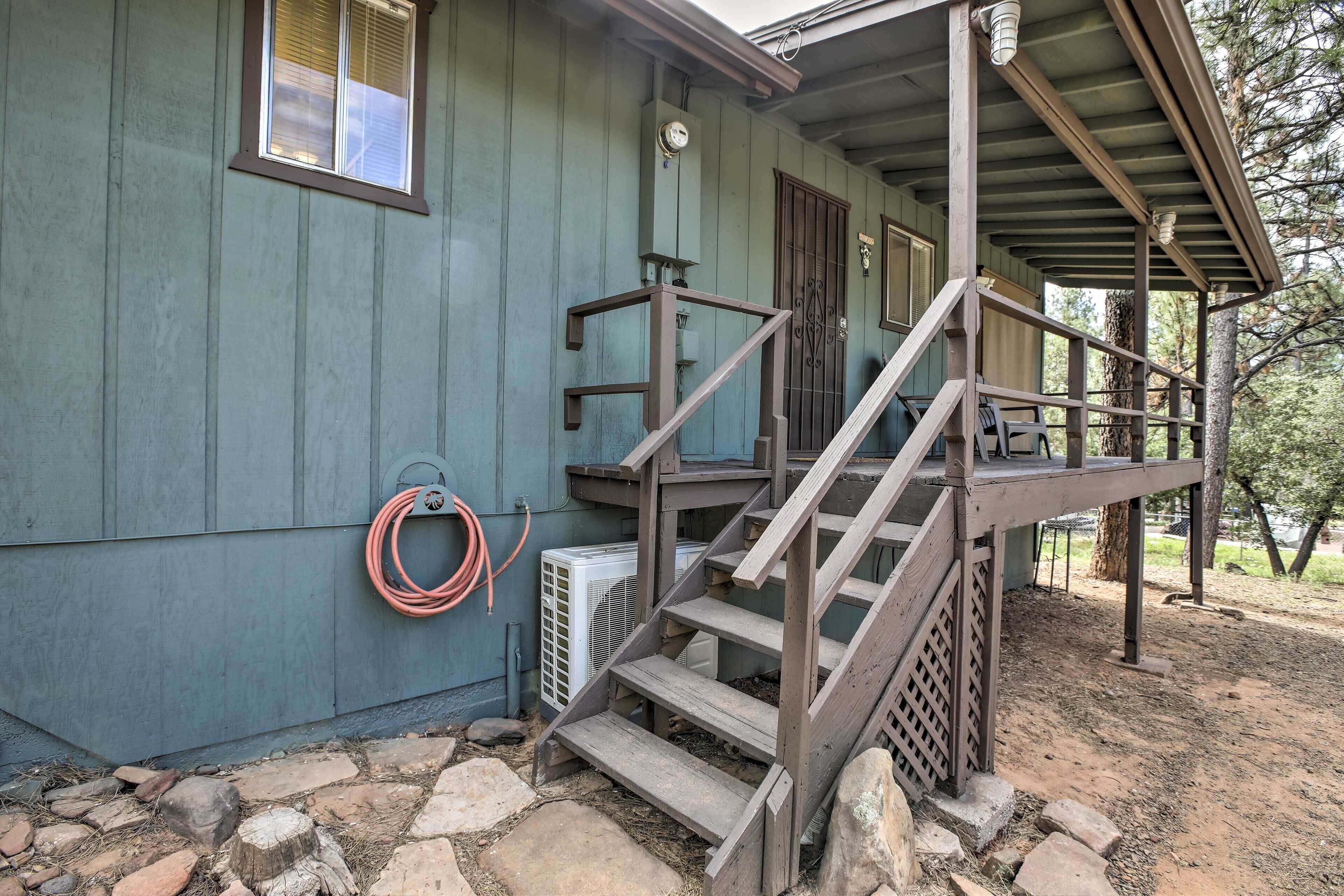 A wooden staircase leading to a porch with a metal railing.