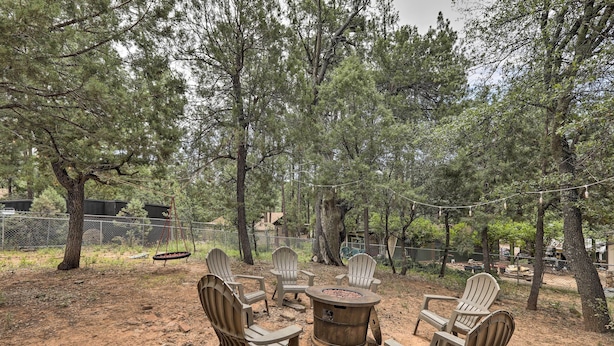 Un espacio al aire libre con sillas Adirondack y un brasero central, rodeado de árboles.
