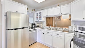 Una cocina moderna con armarios blancos, electrodomésticos de acero inoxidable y un protector de salpicadero de madera.