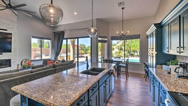 A modern kitchen with granite countertops, dark cabinetry, and a large island. - Putting Green: Golfer's Getaway in Scottsdale (Scottsdale)