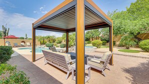 A covered outdoor seating area with a pool, surrounded by greenery and cacti. - Putting Green: Golfer's Getaway in Scottsdale (Scottsdale)