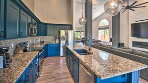 A modern kitchen with blue cabinets, granite countertops, and a central island with a sink. - Putting Green: Golfer's Getaway in Scottsdale (Scottsdale)
