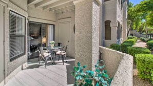 Eine Terrasse mit Tisch, Stühlen, einer Tür und einem Fenster mit Jalousien.