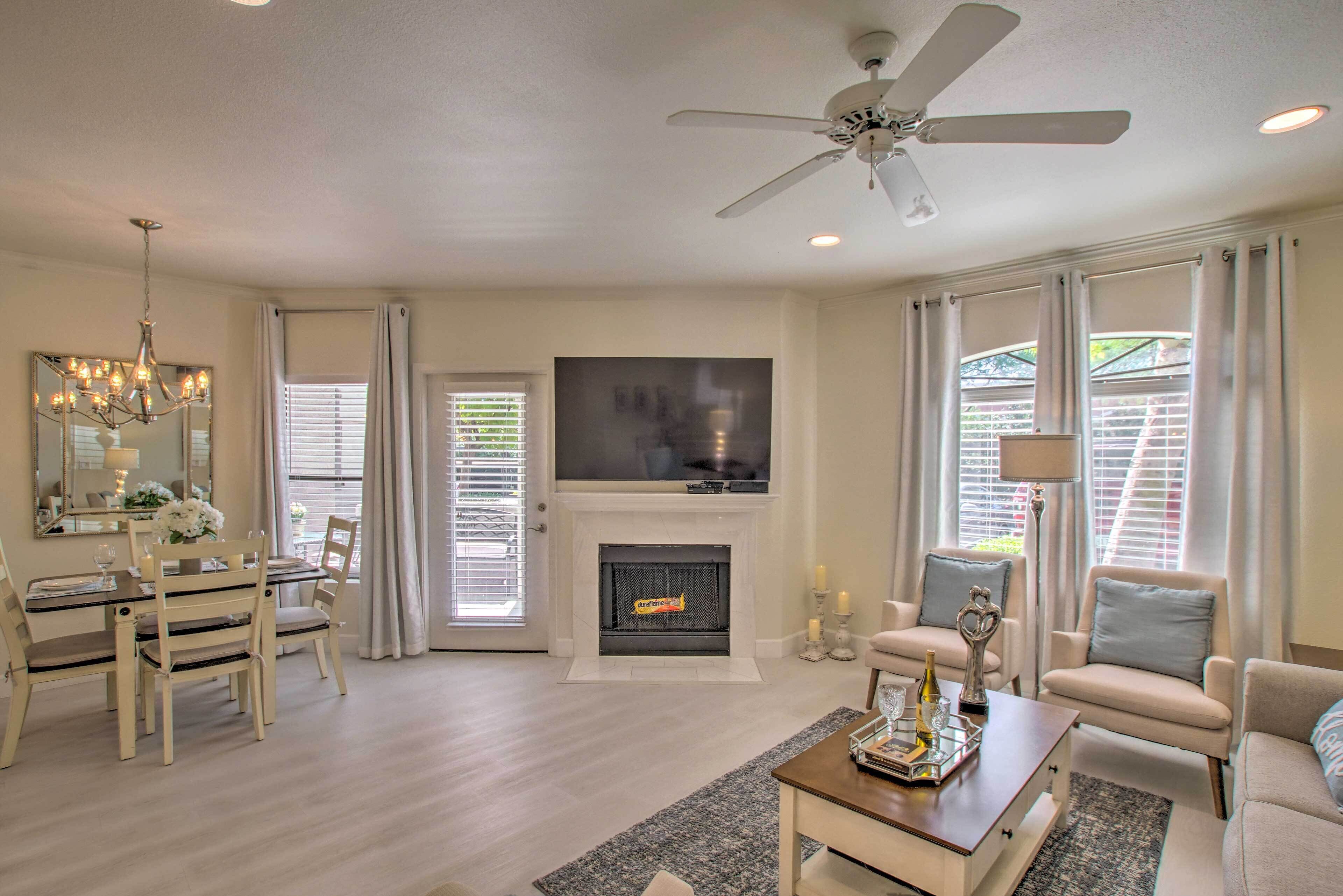 A living room with a fireplace, television, ceiling fan, and seating area.