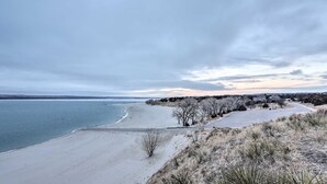 A beach with a clear view of the ocean, a parking area, and a line of trees. - Lake Mcconaughy Getaway With Covered Patio (Lewellen)