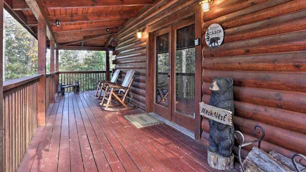 Une cabane en bois avec une véranda, des fauteuils à bascule et une statue d’ours.