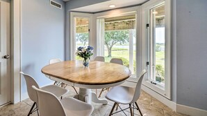 A dining area with a round wooden table, white chairs, and a vase of flowers. - Waterfront Hampstead Home: Dock & Waterway Access! (Hampstead)
