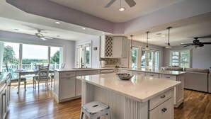 A spacious kitchen with a large island, white cabinetry, and a view to the outside. - Waterfront Hampstead Home: Dock & Waterway Access! (Hampstead)