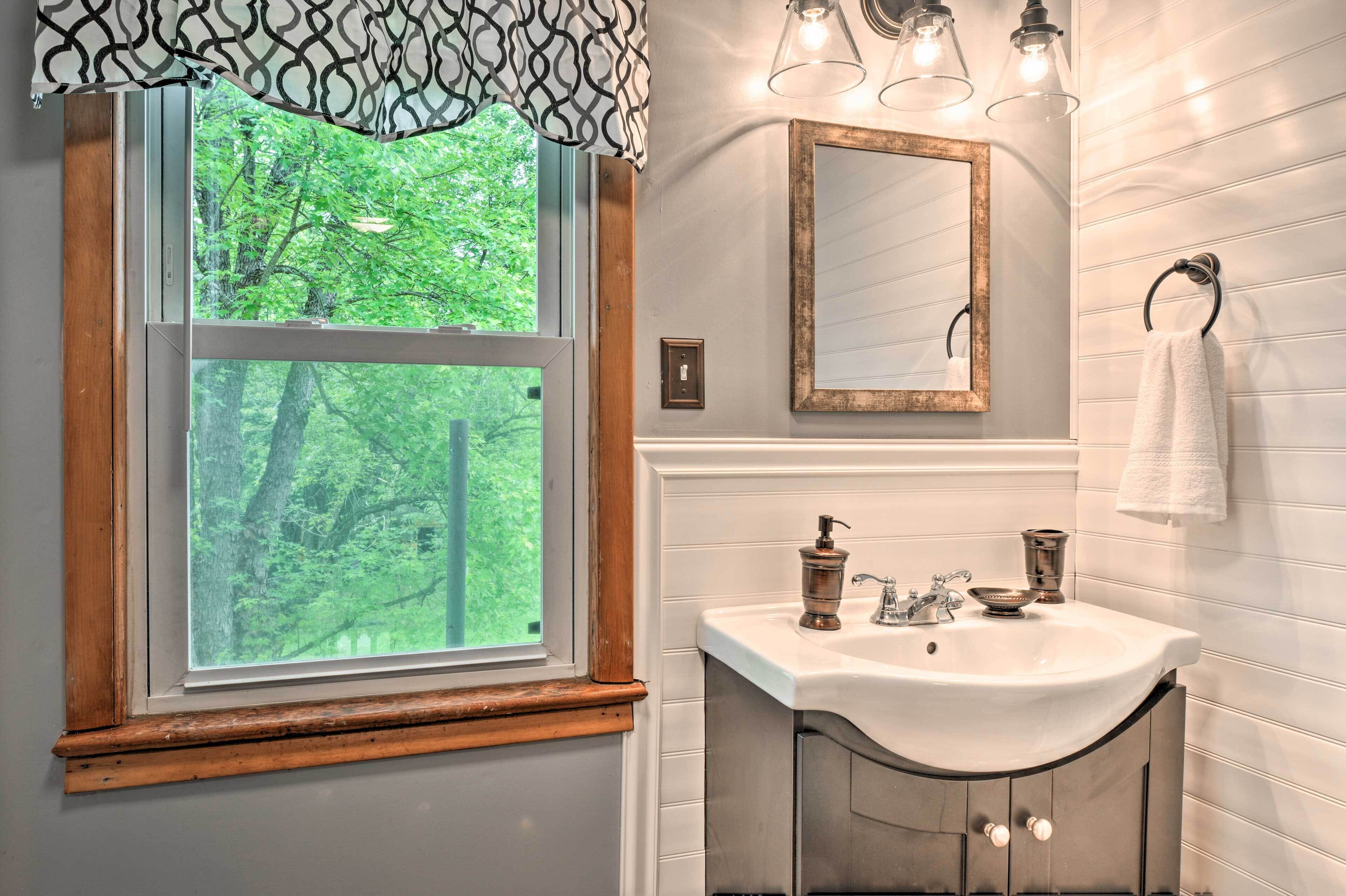 Une salle de bain avec une fenêtre, un lavabo, un miroir et un porte-serviettes.