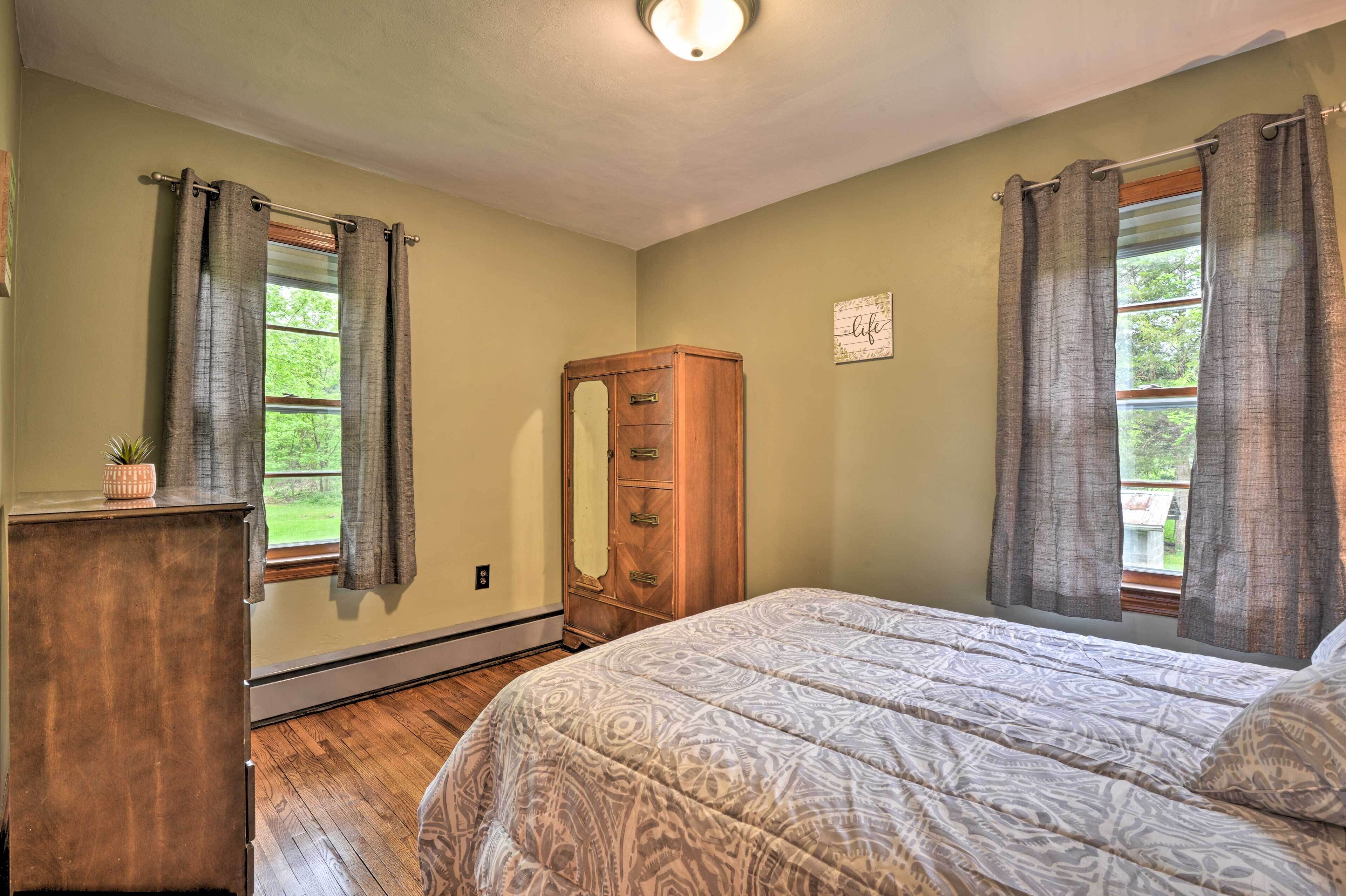 A bedroom with a bed, wooden dresser, and a wardrobe.