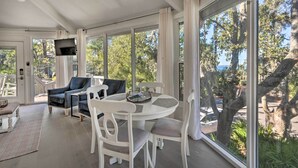 A spacious room with a large window, a dining table with chairs, and a sofa. - Walk to Harbour Town: Airy Treehouse w/ Bikes (Hilton Head Island)