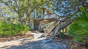 A treehouse with a wooden staircase and a balcony, surrounded by lush greenery. - Walk to Harbour Town: Airy Treehouse w/ Bikes (Hilton Head Island)