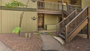 A building with a wooden staircase leading to a balcony, a door labeled "BOUDEAU," and a small tree in the foreground. - Patio & Fireplace: Country Club Pinetop Condo! (Pinetop)