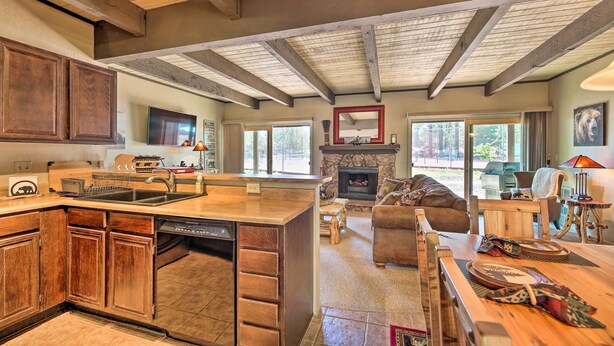 A spacious kitchen with wooden cabinets, a dishwasher, and a large island. There is a fireplace in the living area with a stone surround, and a cozy seating area with a sofa and a coffee table. - Patio & Fireplace: Country Club Pinetop Condo! (Pinetop)