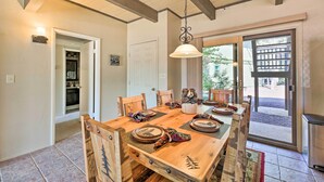 A dining area with a wooden table, chairs, and a hanging light fixture. - Patio & Fireplace: Country Club Pinetop Condo! (Pinetop)