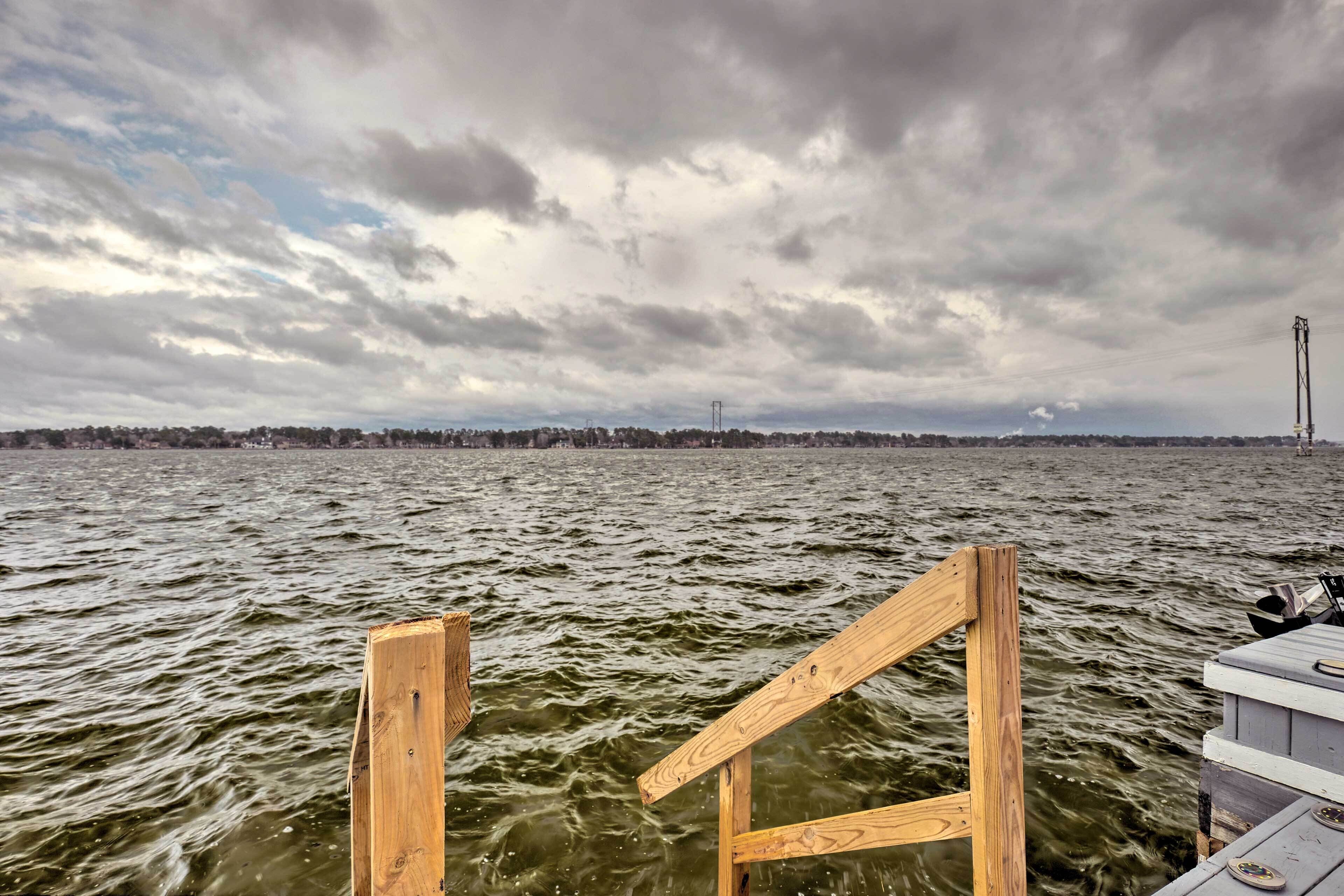 A wooden dock extending into a body of water with a cloudy sky above.