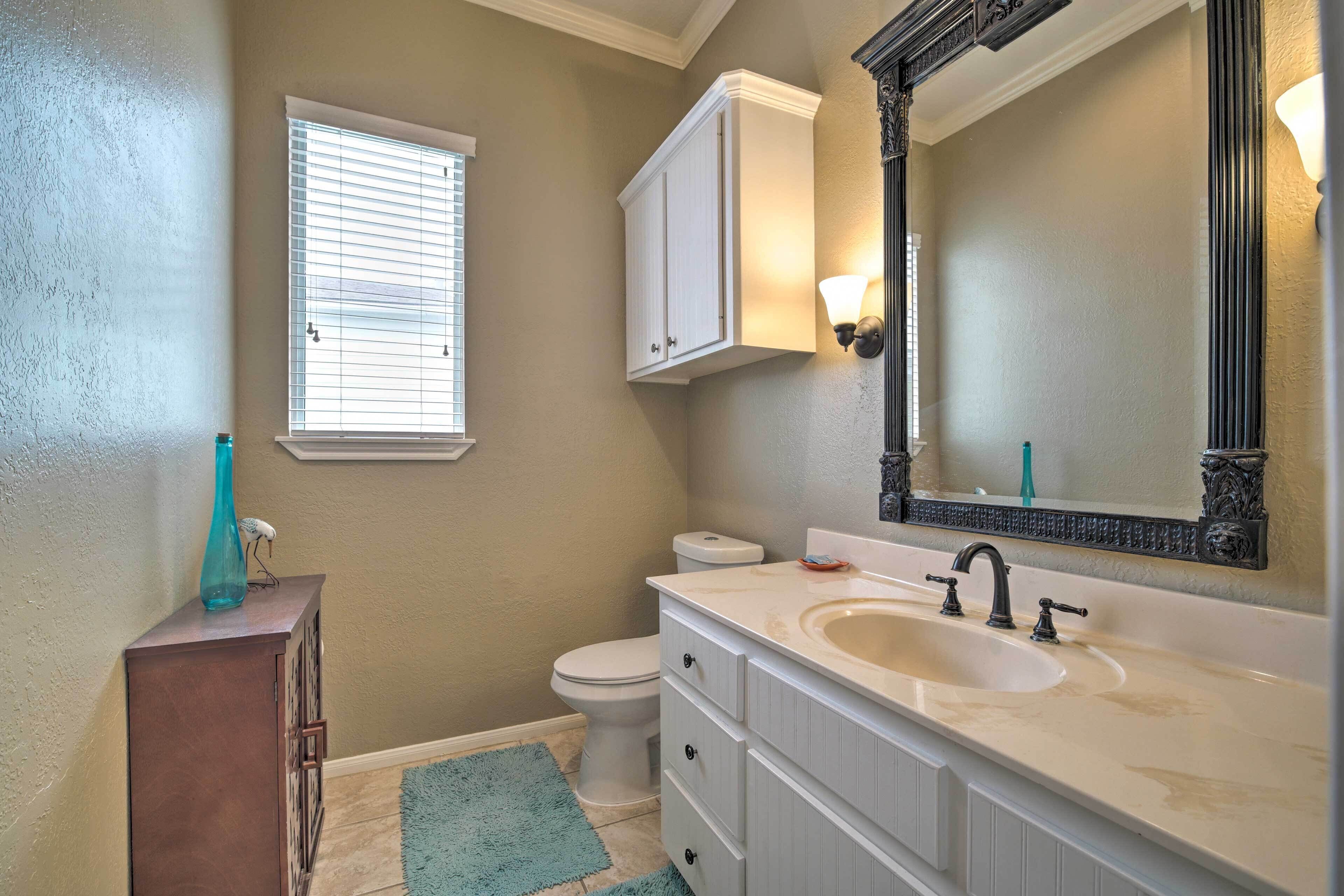 A bathroom with a toilet, a sink with a mirror, and a cabinet.
