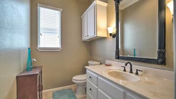 A bathroom with a toilet, a sink with a mirror, and a cabinet.