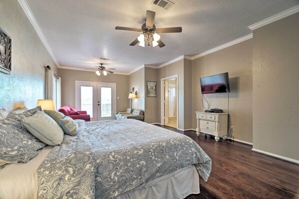 A bedroom with a large bed, a ceiling fan, a television, and a dresser. - Waterfront Lake Conroe Getaway w/ Multiple Decks! (Montgomery)