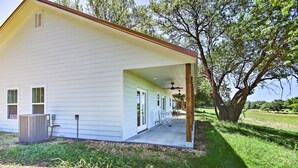 Une maison de plain-pied avec un porche couvert, un système de climatisation central et un arbre en arrière-plan.