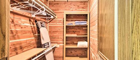 A wooden interior with a towel rack, a bench, and a shelf with towels.