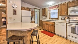 A kitchen with wooden cabinets, a white refrigerator, a stove, and a sink. - Cozy Crosby Cabin Near Serpent Lake + Main St (Crosby)
