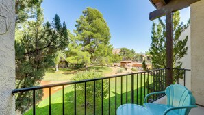 A balcony with a view of a green lawn and trees, a table, and two chairs. - Mtn-view Condo w/ Hot Tub Access in Sedona! (Sedona)