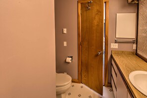 Ein Badezimmer mit Holztür, Toilette, Waschbecken und Spiegel.