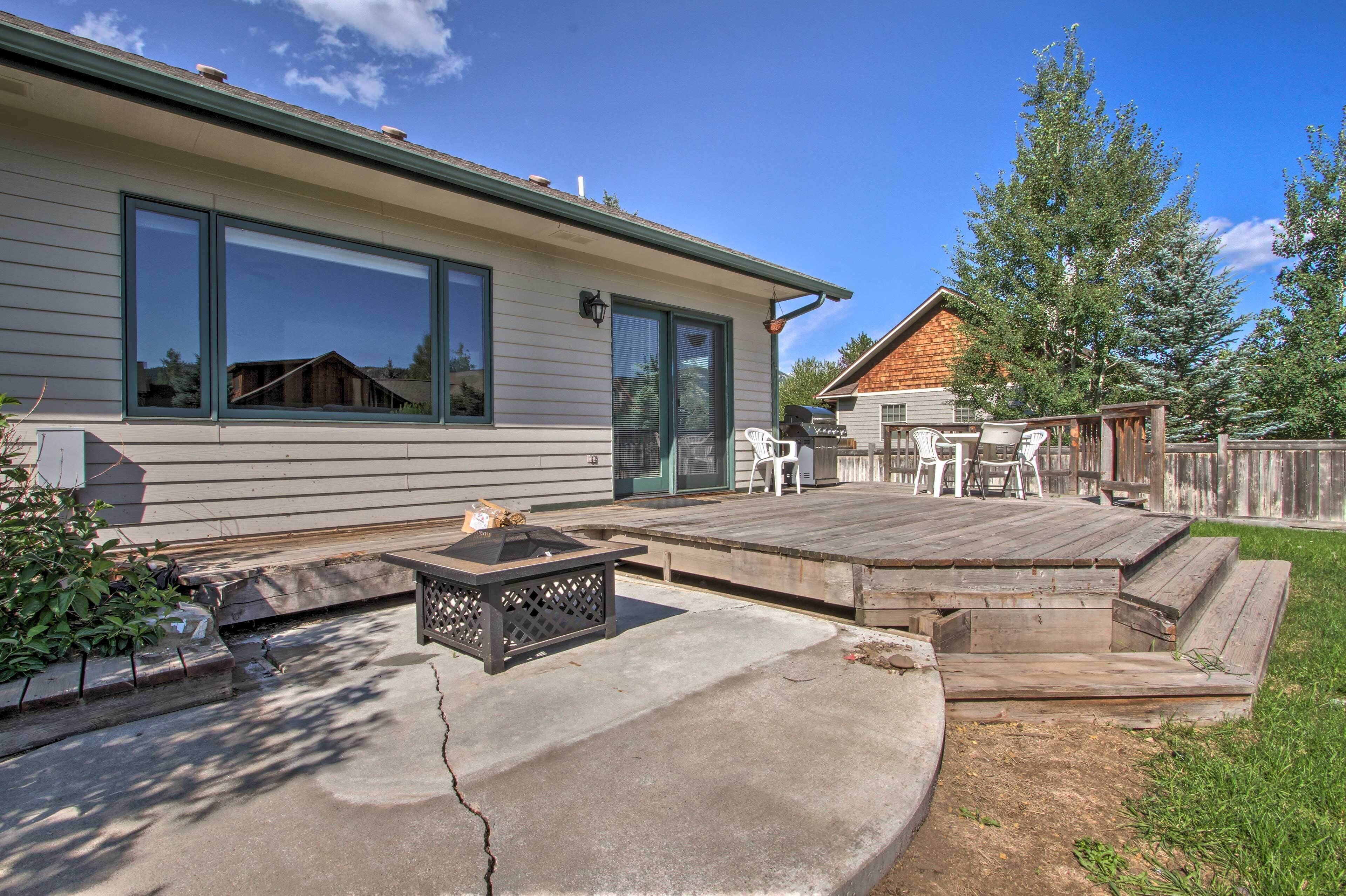 A residential deck with outdoor seating, a fire pit, and a view of a neighboring house.
