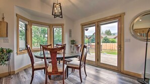 A dining area with a round table and chairs, large windows, and a view of the backyard. - 6 Mi to Big Sky Resort! Group Retreat w/ Mtn Views (Big Sky)