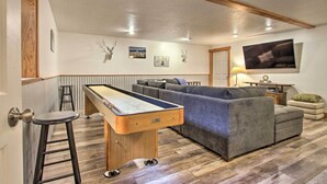A living room with a pool table, grey sofa, and a television mounted on the wall. - 6 Mi to Big Sky Resort! Group Retreat w/ Mtn Views (Big Sky)