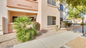 A multi-story residential building with balconies, a gravel driveway, and landscaping including a palm tree and shrubs. - Bright Phoenix Condo - 3 Mi to State Farm Stadium! (Phoenix)