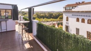 A balcony with a table and chairs, a view of a garden, and a building with arched windows. - Spectacular Penthouse in the Mosque (Cordoba)