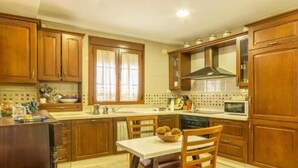 Una cocina con armarios de madera, microondas y una mesa de comedor con sillas.