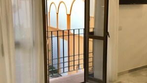 Een kamer met een schuifdeur naar een balkon met een metalen hekwerk.