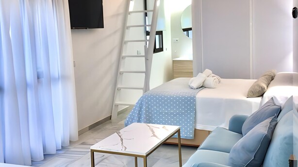 Een slaapkamer met een stapelbed, een bureau, een stoel, een televisie en een raam met gordijnen.