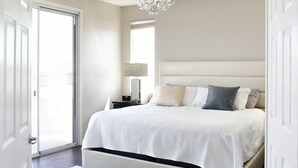 A bedroom with a large bed, a nightstand, a lamp, and a chandelier. -  Luxury Oasis Near the Las Vegas Strip – Sleeps Large Groups in Style (Las Vegas)