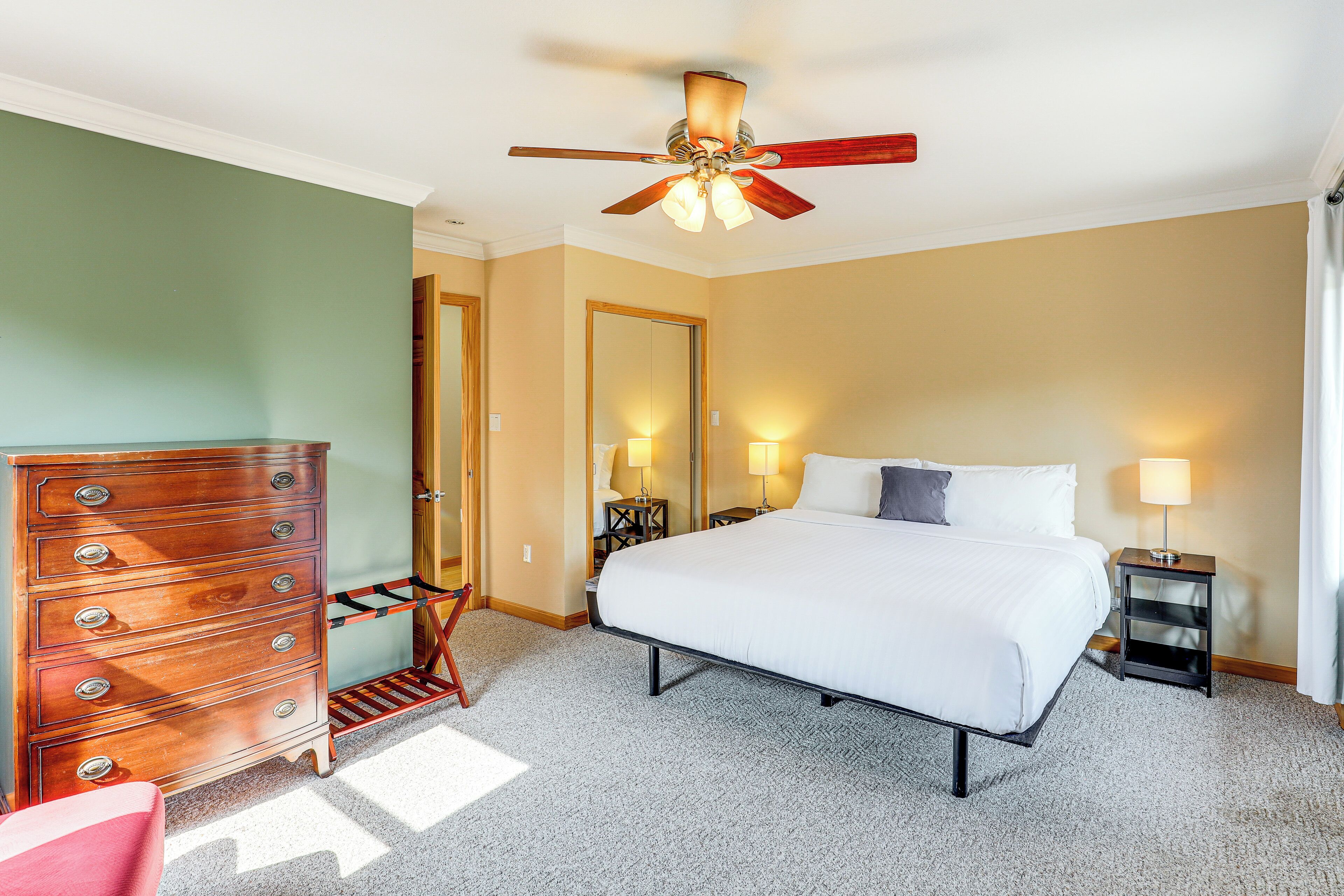 A hotel room with a bed, dresser, ceiling fan, and two bedside lamps.
