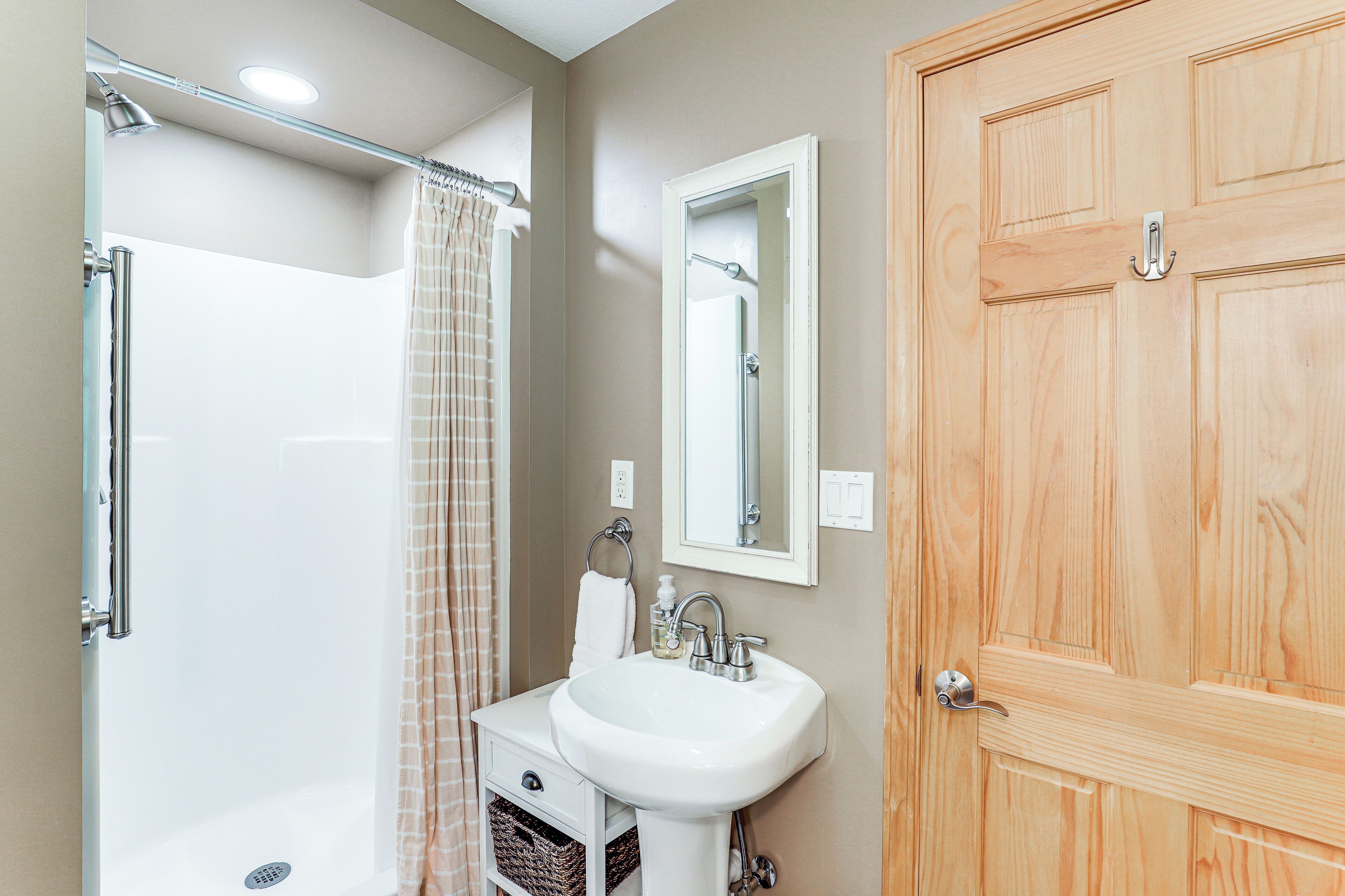 Une salle de bain avec une douche, un lavabo et une porte en bois.