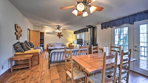 A cozy living room with a wooden dining table, several chairs, a sofa, and a ceiling fan. - Secluded Bryson City Home w/ Deck, Steps to Creek! (Bryson City)