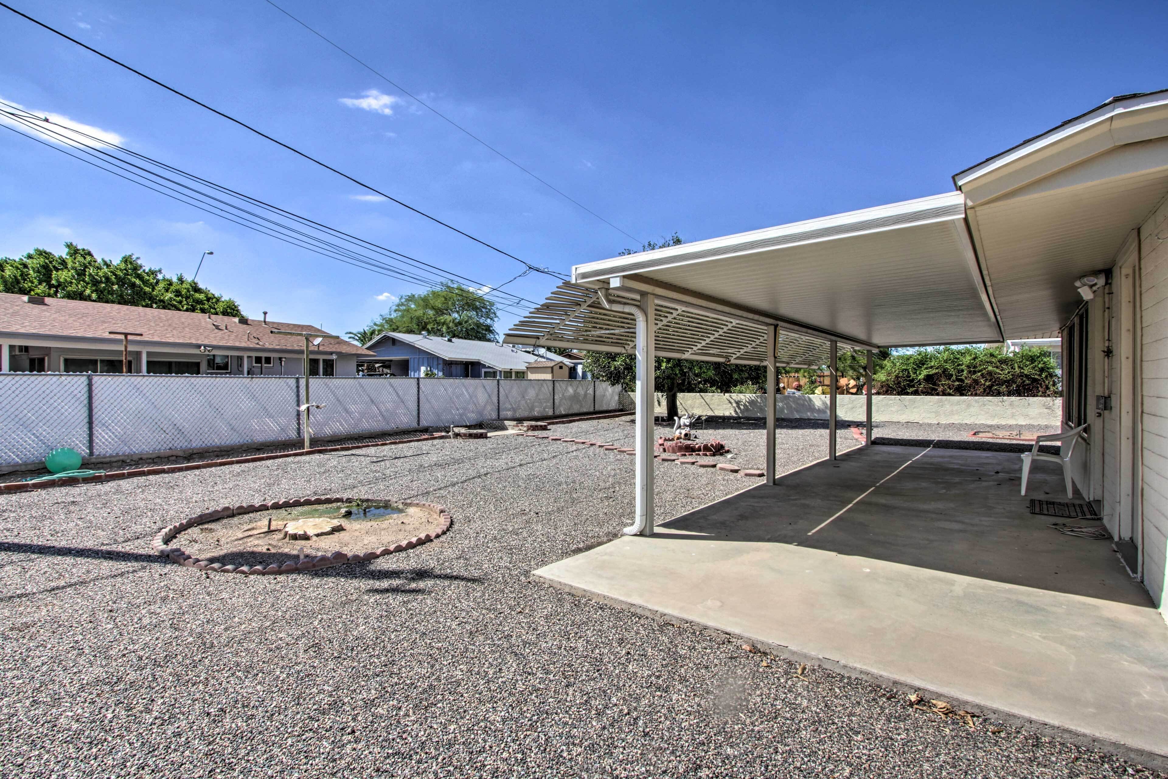 A covered outdoor area with a gravel path, a circular garden feature, and a building with a white exterior.