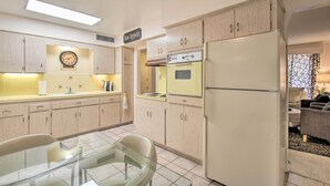 Une cuisine avec des meubles de rangement en bois, un réfrigérateur, un four et une table à manger avec des chaises.