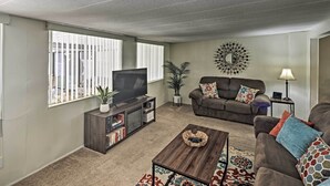 A living room with a sofa, a coffee table, a TV, and a bookshelf. - Restful Riverfront Retreat w/ Private Dock + Patio (Bullhead City)