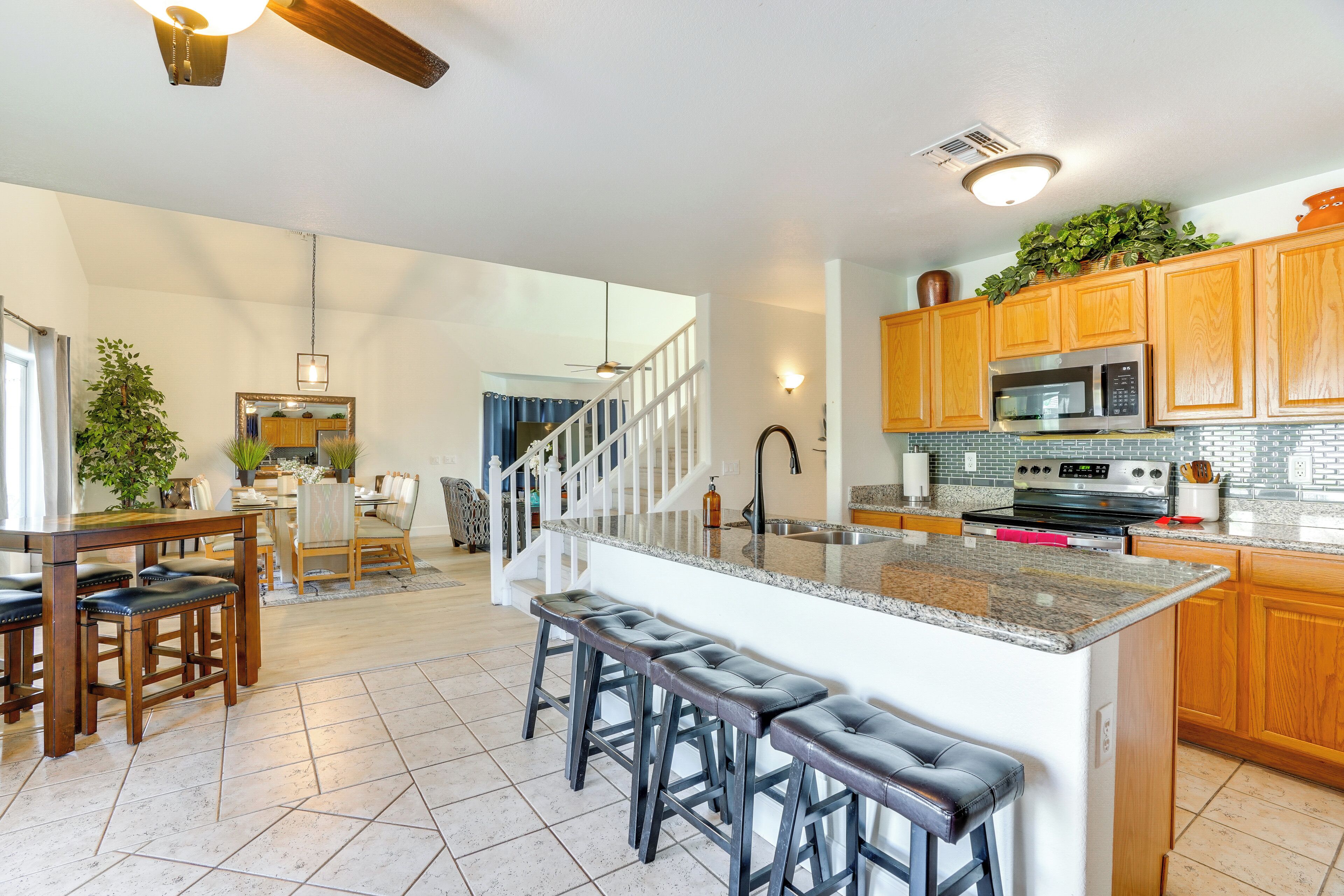 A spacious kitchen with a large island, wooden cabinets, and a stainless steel microwave.